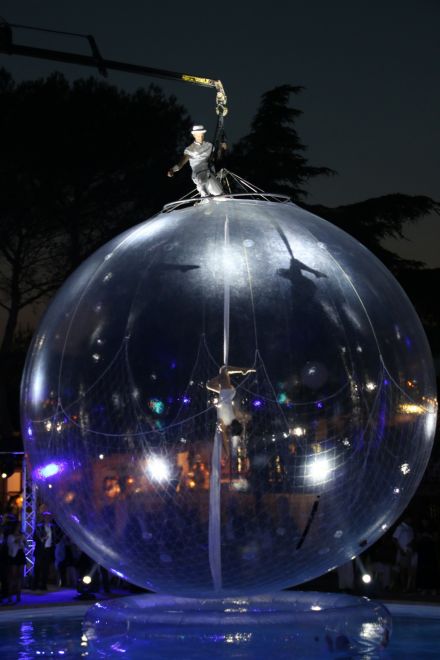 Sphère transparente éclairée pendant un spectacle nocturne avec des artistes