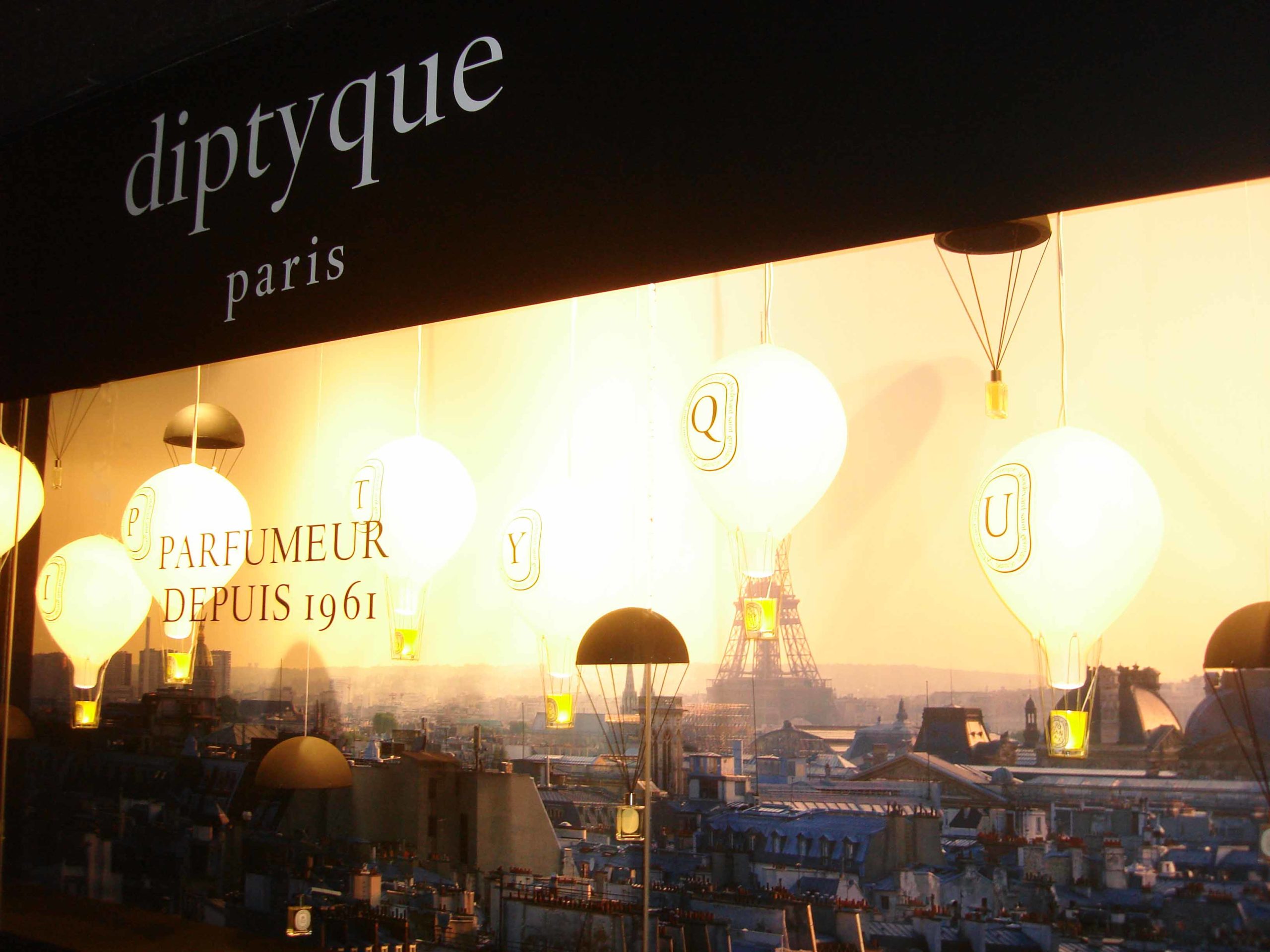 Vitrine Diptyque aux Galeries Lafayette avec montgolfières gonflables au-dessus de Paris