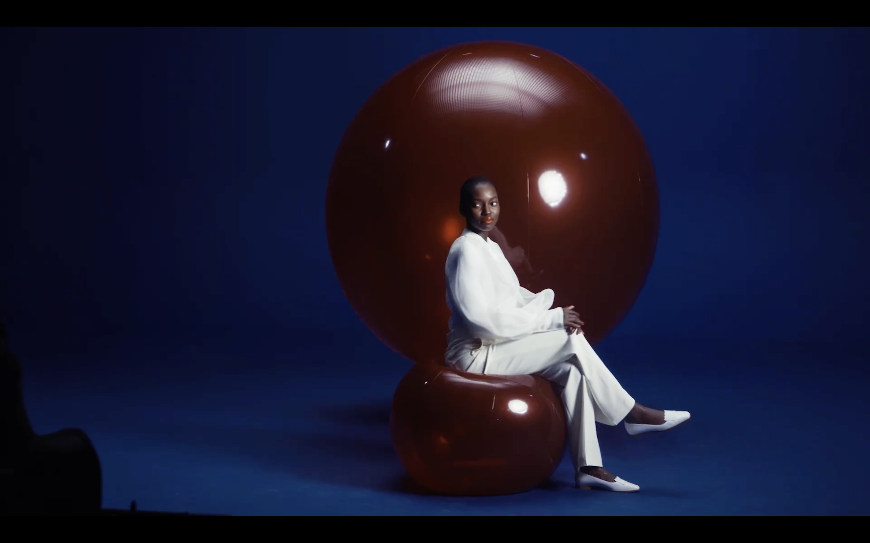 Vue du tournage Air France avec une silhouette assise et deux grandes bulles rouges devant un fond bleu